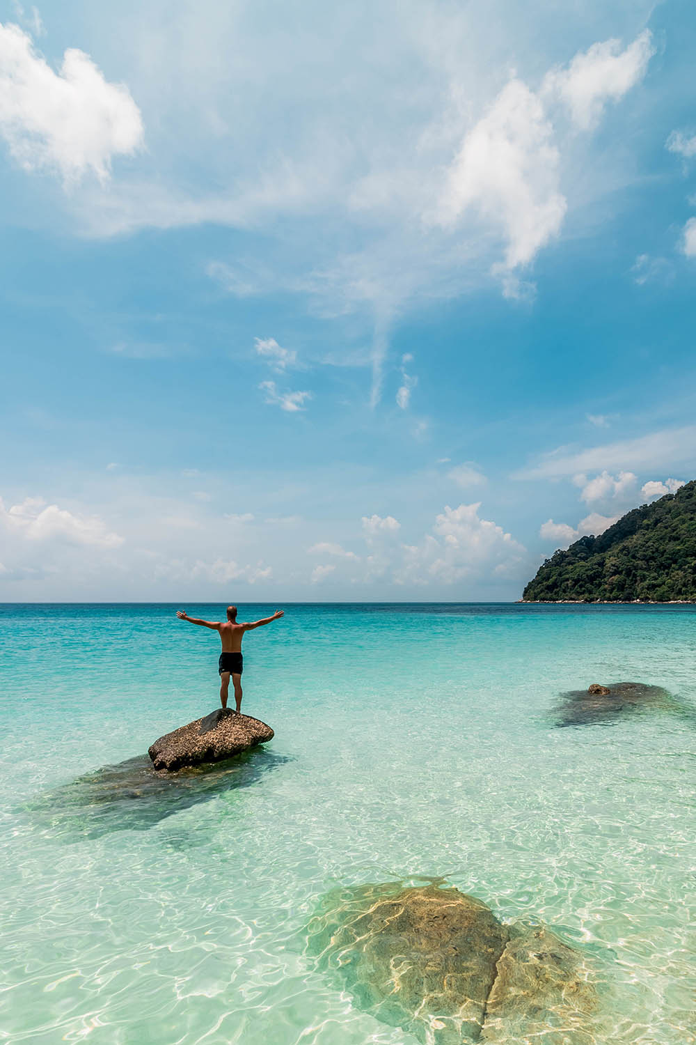 An incredible shot of a man getting ready to swim in a tranquil, peaceful beach